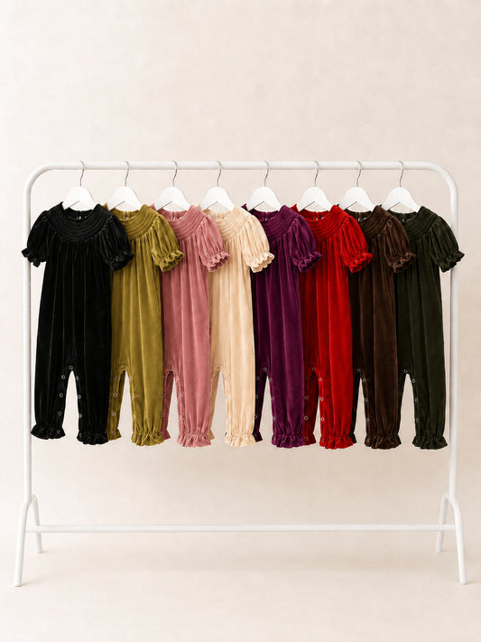 Baby girl smocked velvet holiday rompers in eight colors hanging on a clothing rack - Alternative view