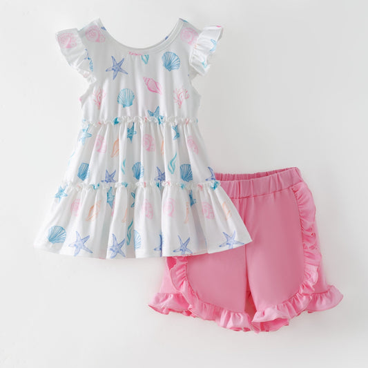 Children's outfit with a patterned top and pink shorts on a white background