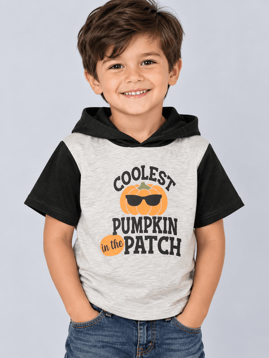 Coolest Pumpkin in the Patch halloween top graphic on child, paired with blue jeans, against a solid light gray background. 