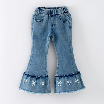 Blue denim jeans with ruffled hem and bow details on a white background