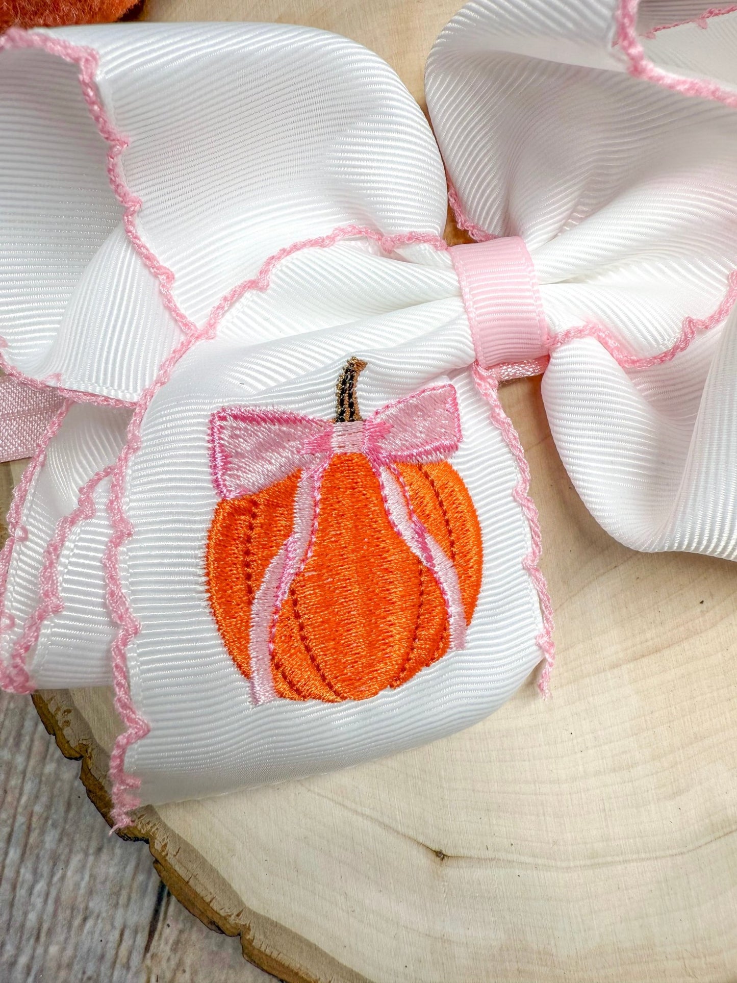Close up of pumpkin with pink coquette bow embroidery on headband ribbon
