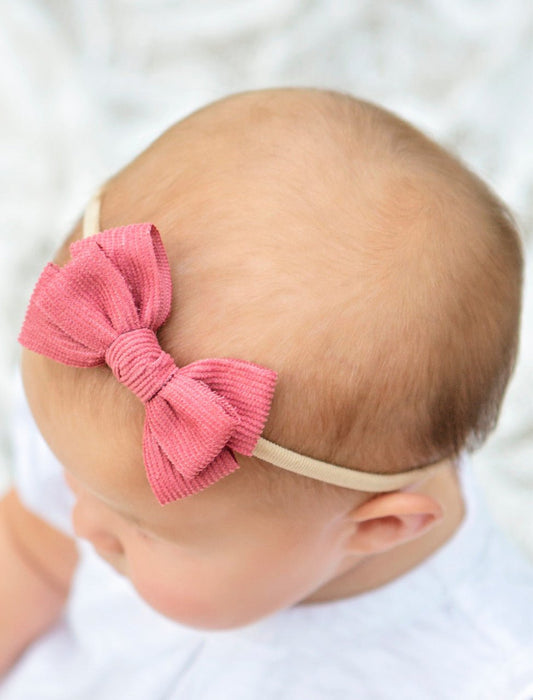 Girl wearing a pink stretchy corduroy bow headband