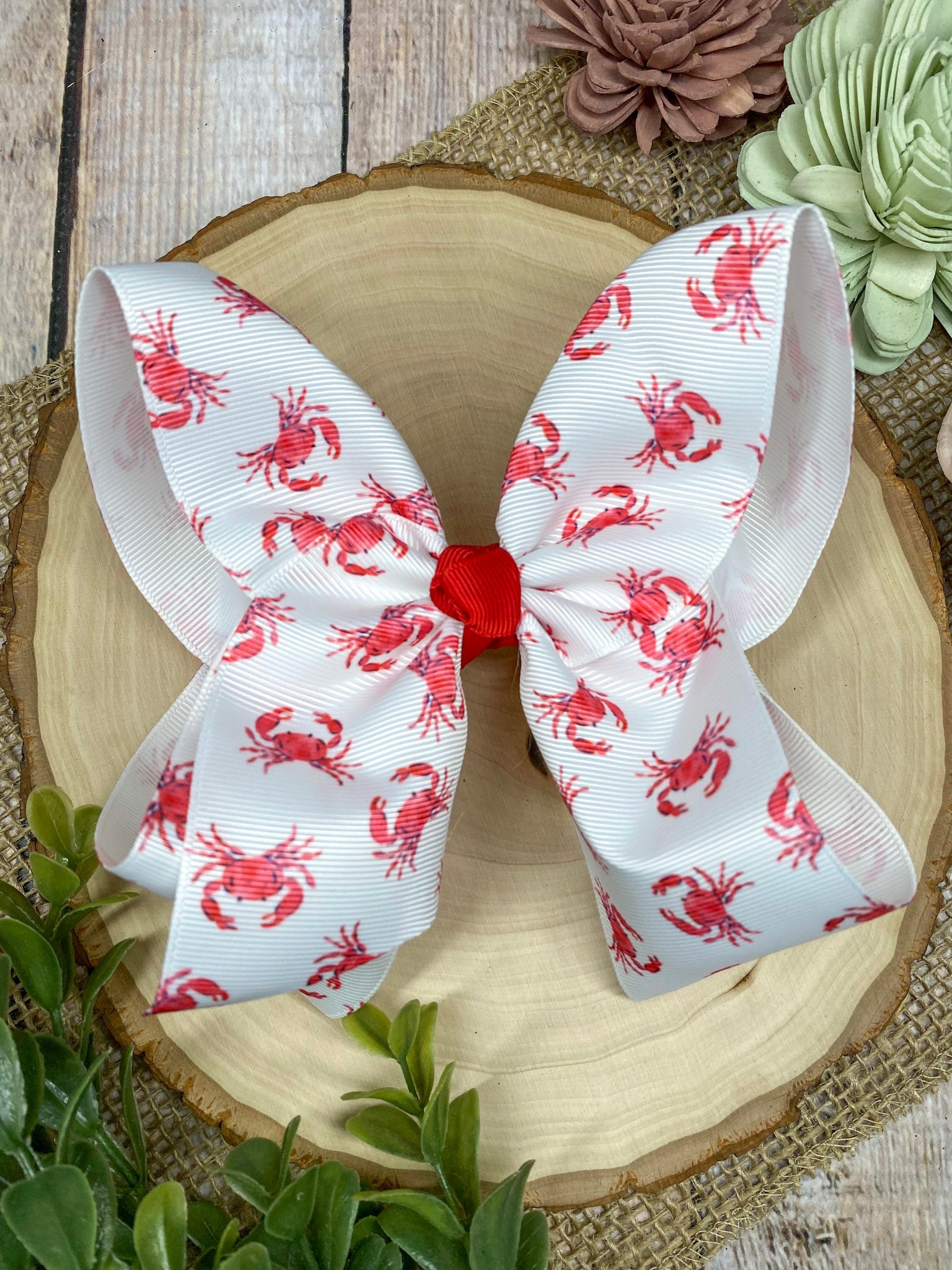 White hair bow with red patterns on a decorative plate with flowers in the background