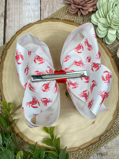 White hair bow with red patterns on a decorative plate with flowers in the background
