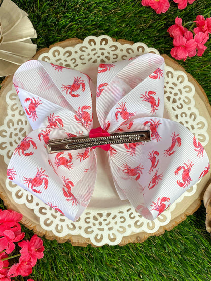 White hair bow with red patterns on a decorative plate with flowers in the background