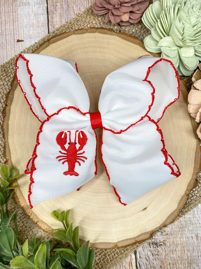 The Crawfish & Lobster Embroidered Moonstitch Hair Bow on a wooden background