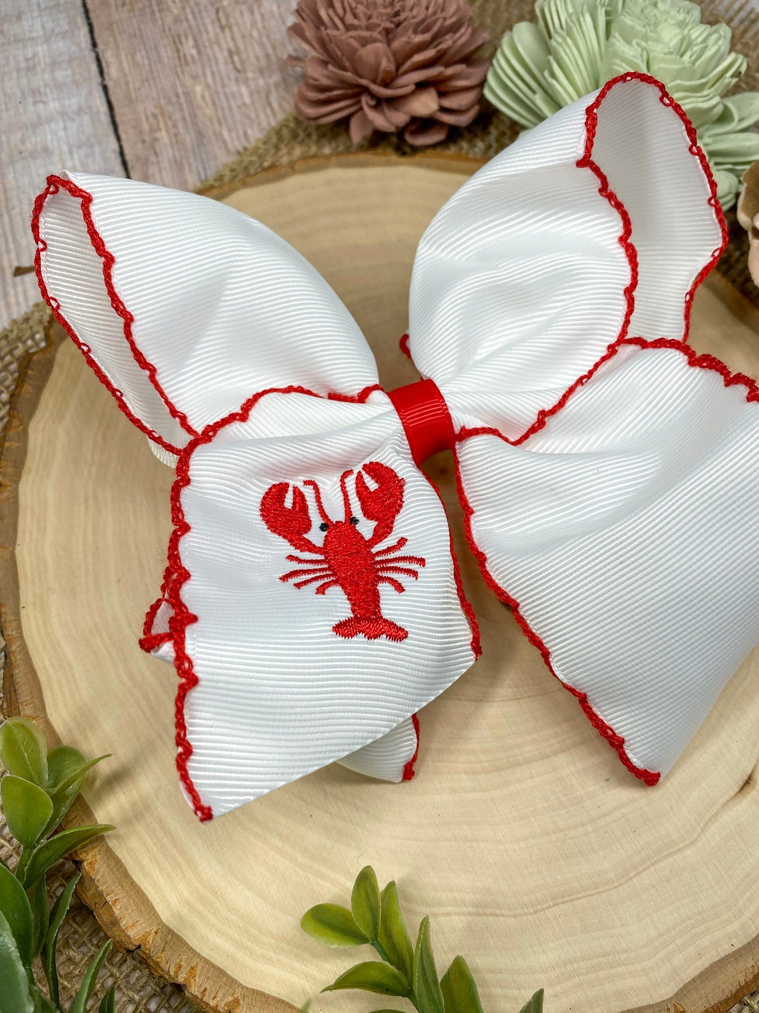 The Crawfish & Lobster Embroidered Moonstitch Hair Bow on a wooden background