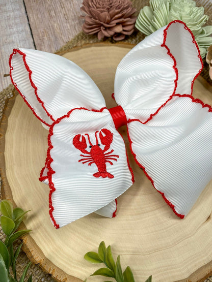 The Crawfish & Lobster Embroidered Moonstitch Hair Bow on a wooden background