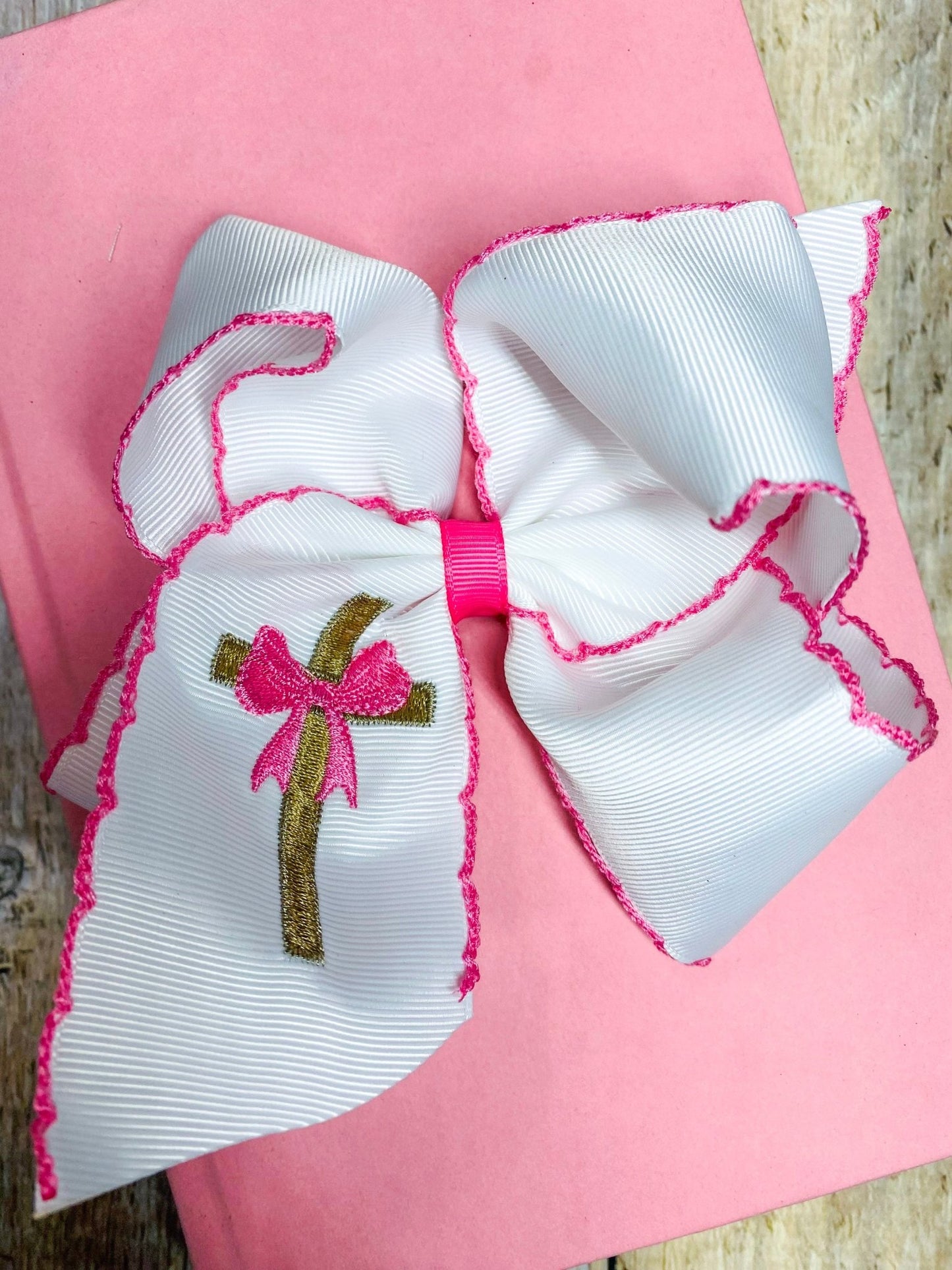 Large white and pink bow with a small embroidered design on a pink background