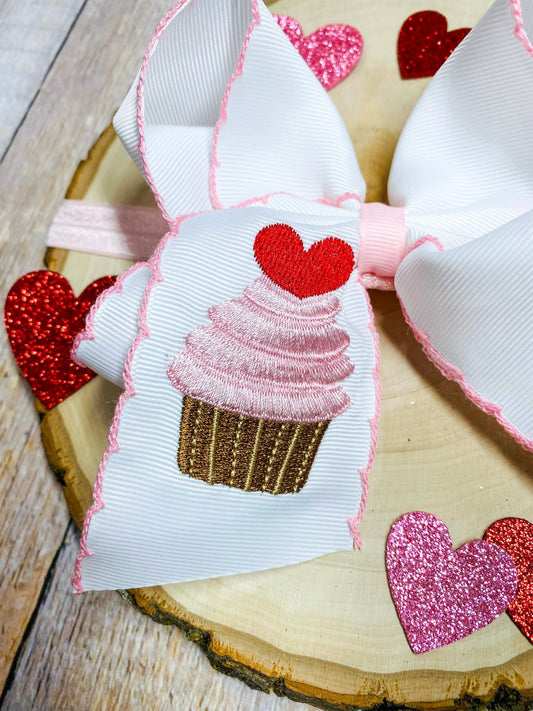 Bow with a cupcake design and heart details on a wooden surface - Alternative view