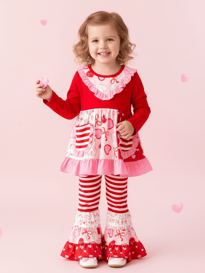Child wearing a red and white outfit with hearts on a pink background