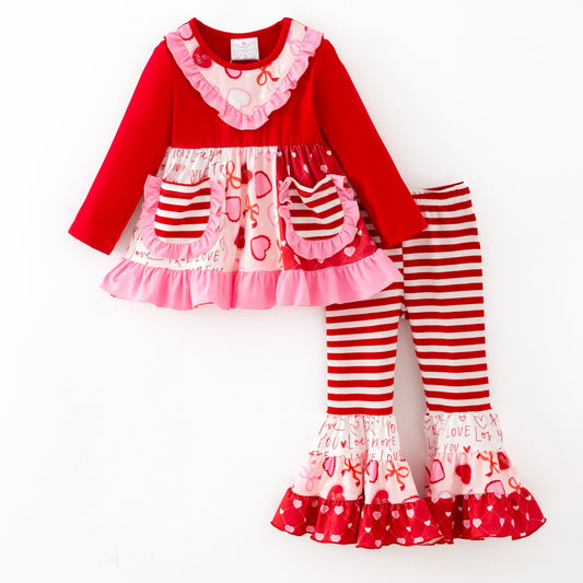 Children's outfit with red and pink dress and striped pants on a white background