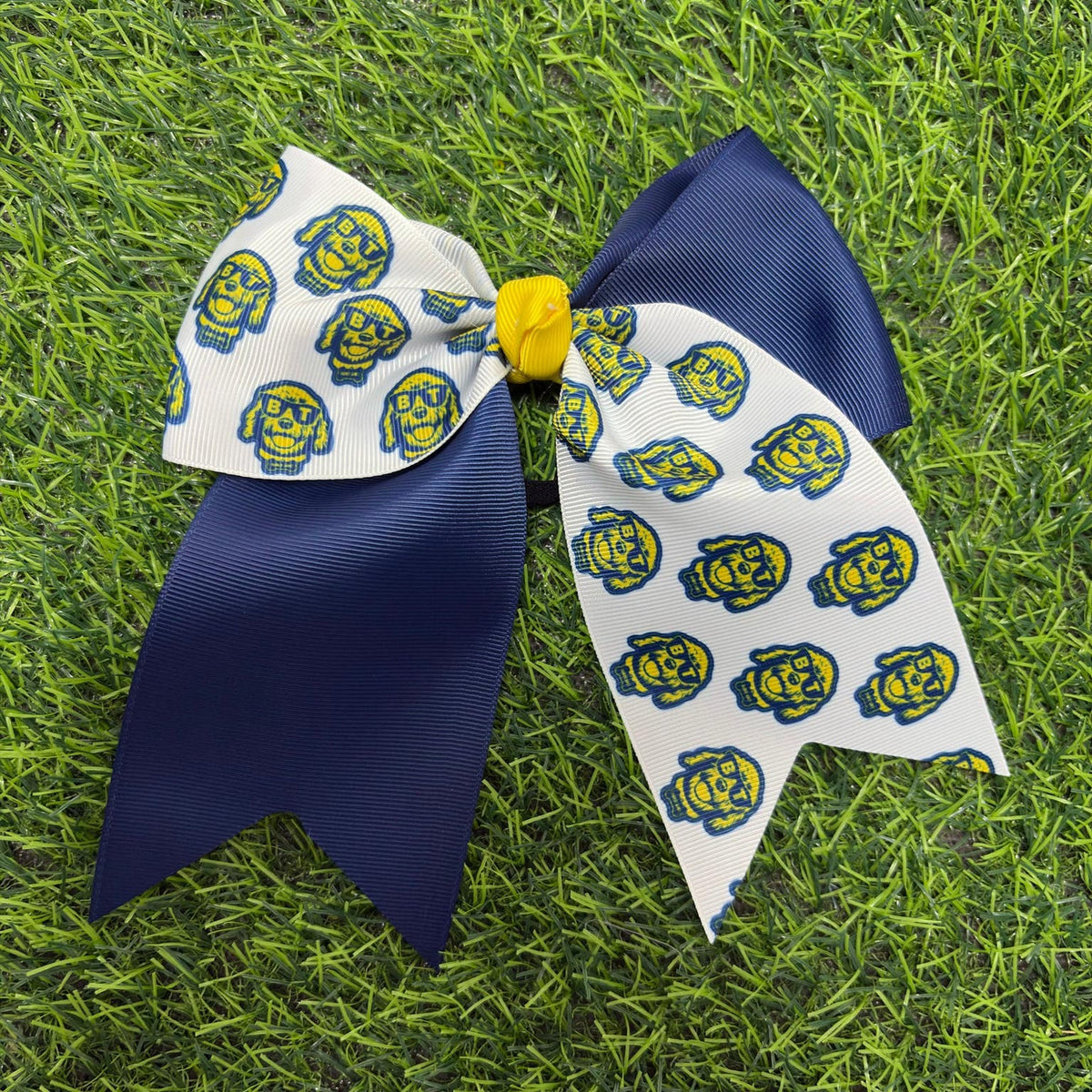 Navy and white custom printed cheer bow with yellow center on grass