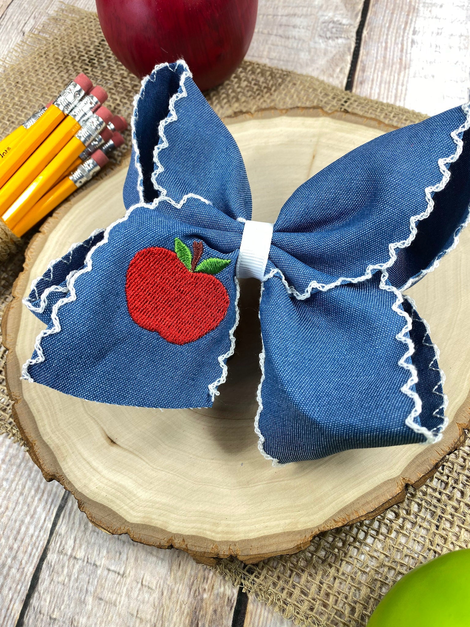 Denim Apple Embroidered Moonstitch Hair Bow on a wooden background
