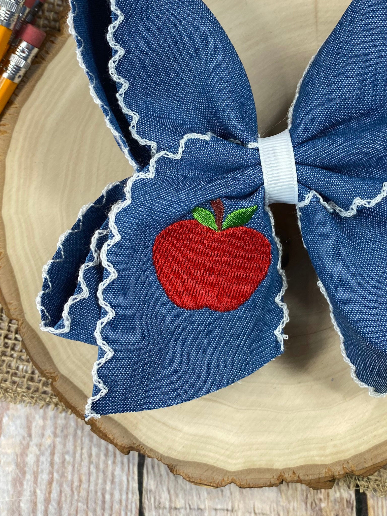 Denim Apple Embroidered Moonstitch Hair Bow on a wooden background