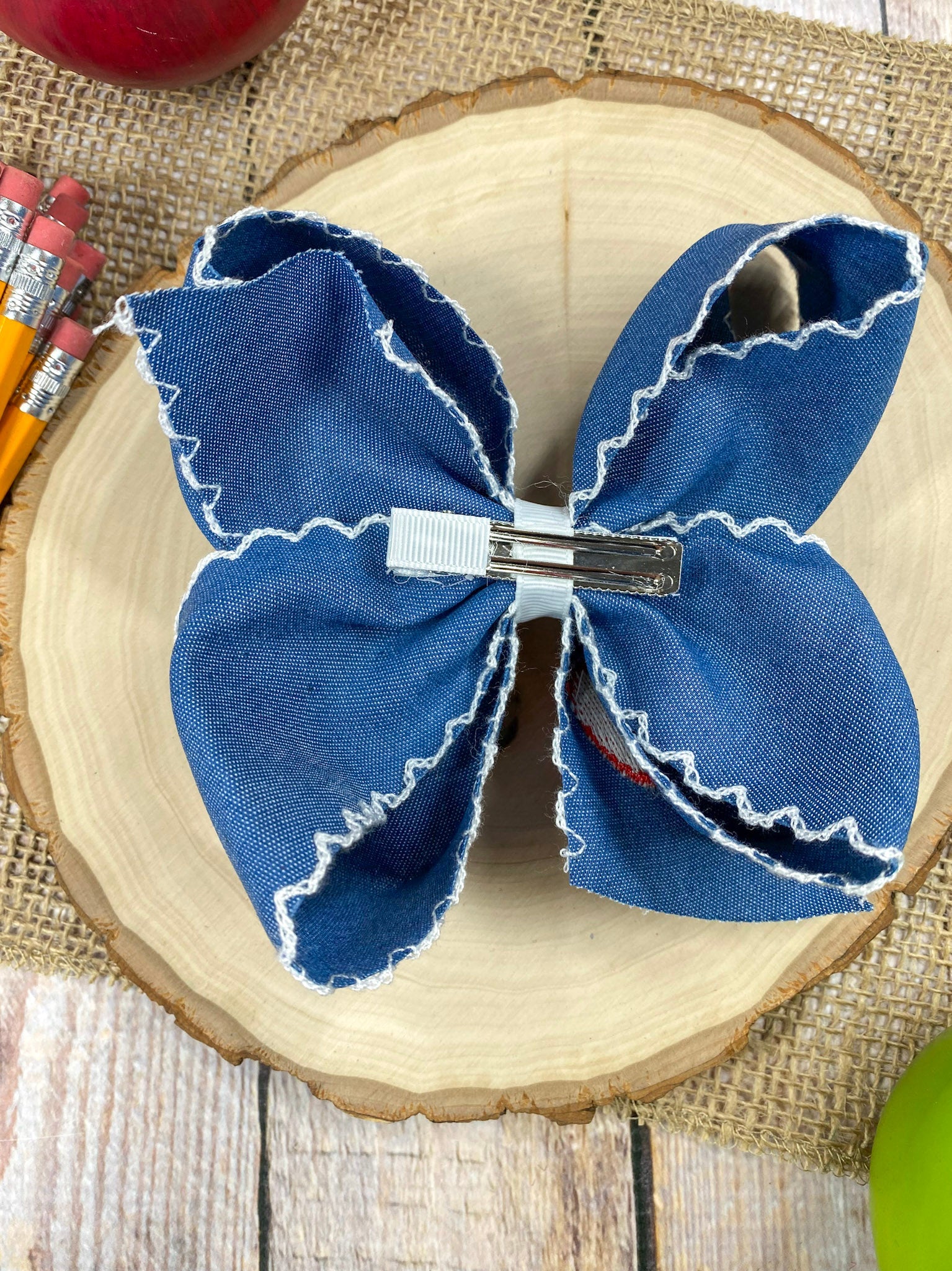 Denim Apple Embroidered Moonstitch Hair Bow on a wooden background