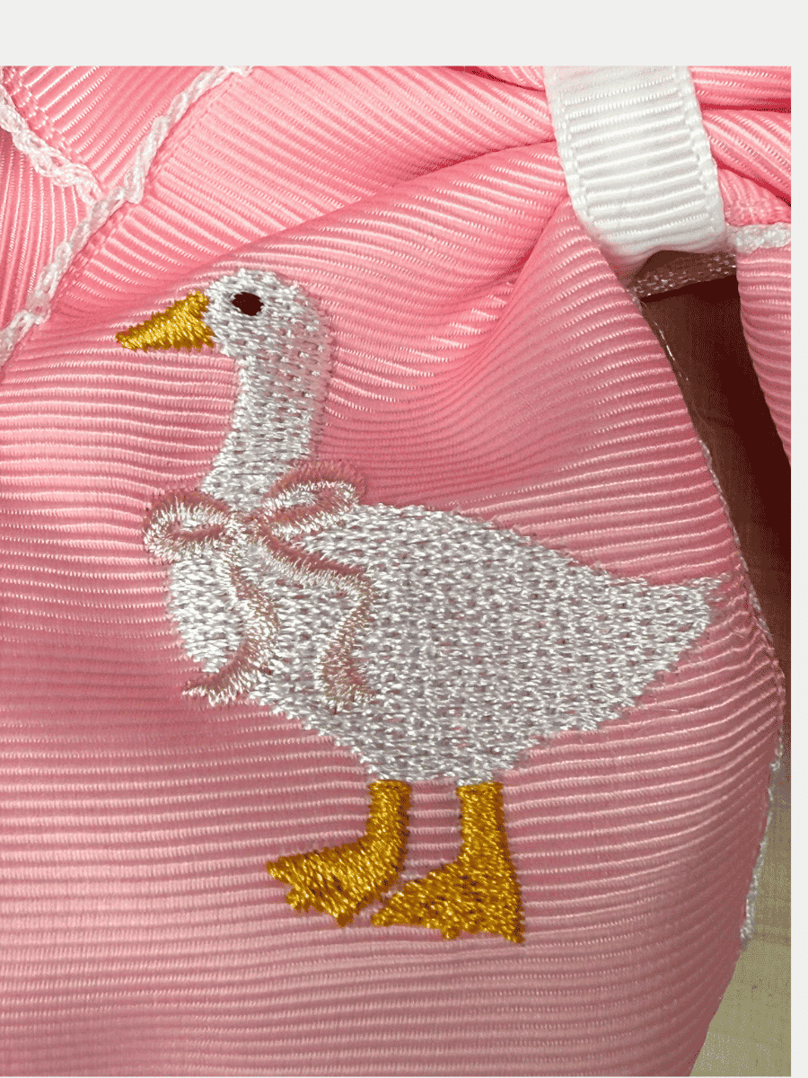 Close-up of embroidered white goose on pink moonstitch hair bow