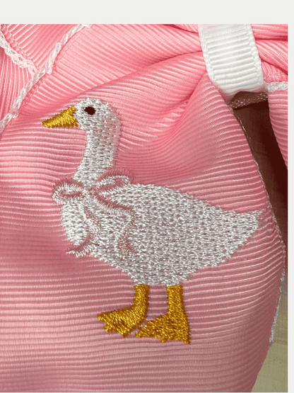 Close-up of embroidered white goose on pink moonstitch hair bow