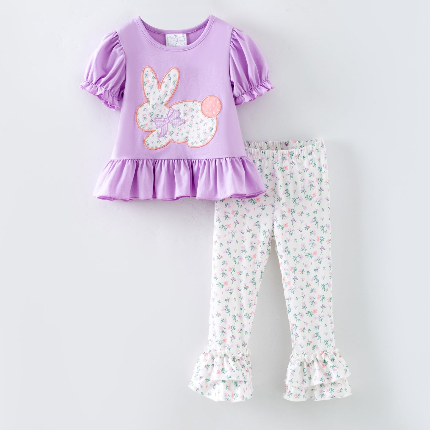 Easter outfit with purple top and floral pants on a white background