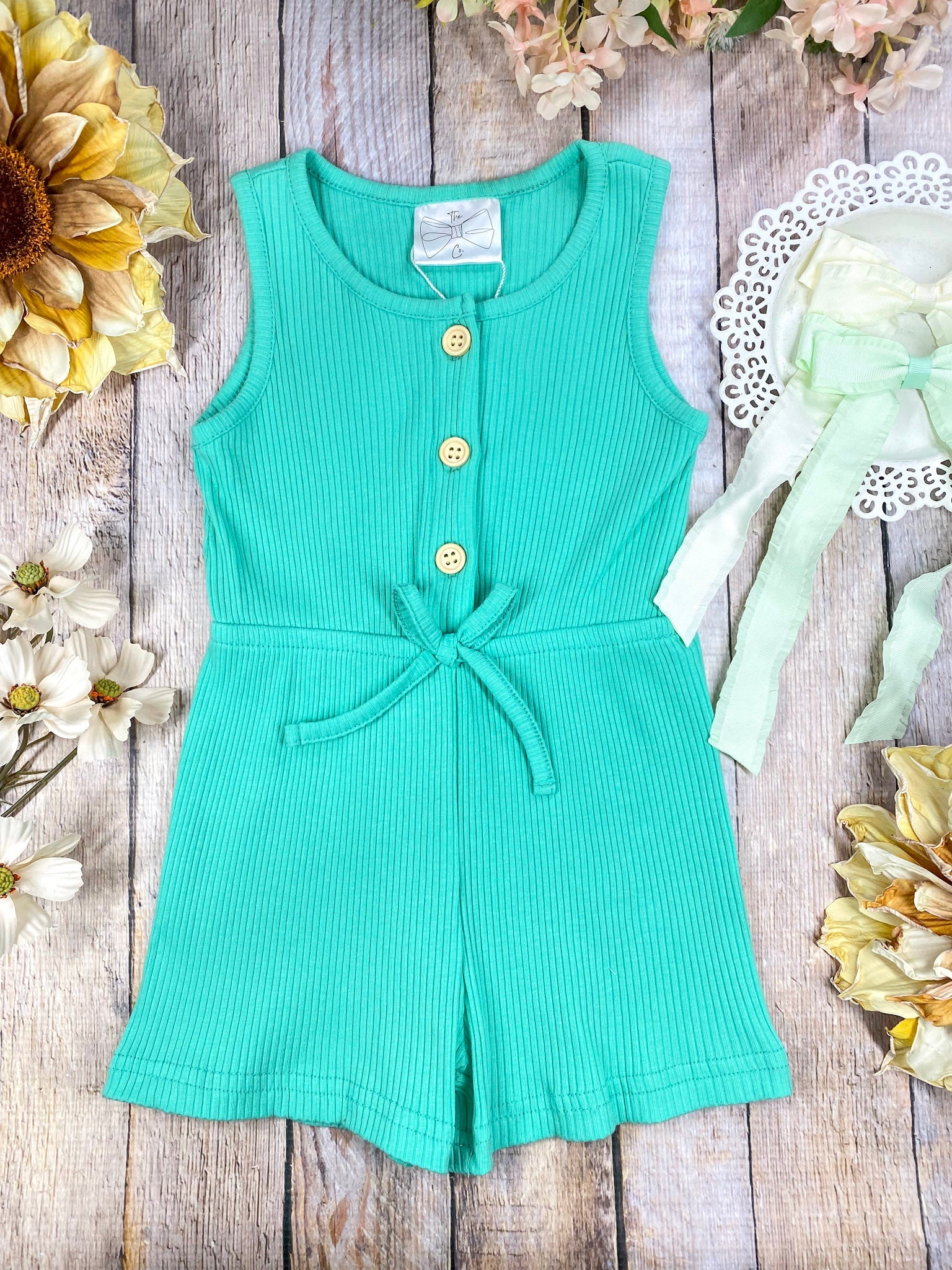 colorful romper in green on a wooden background