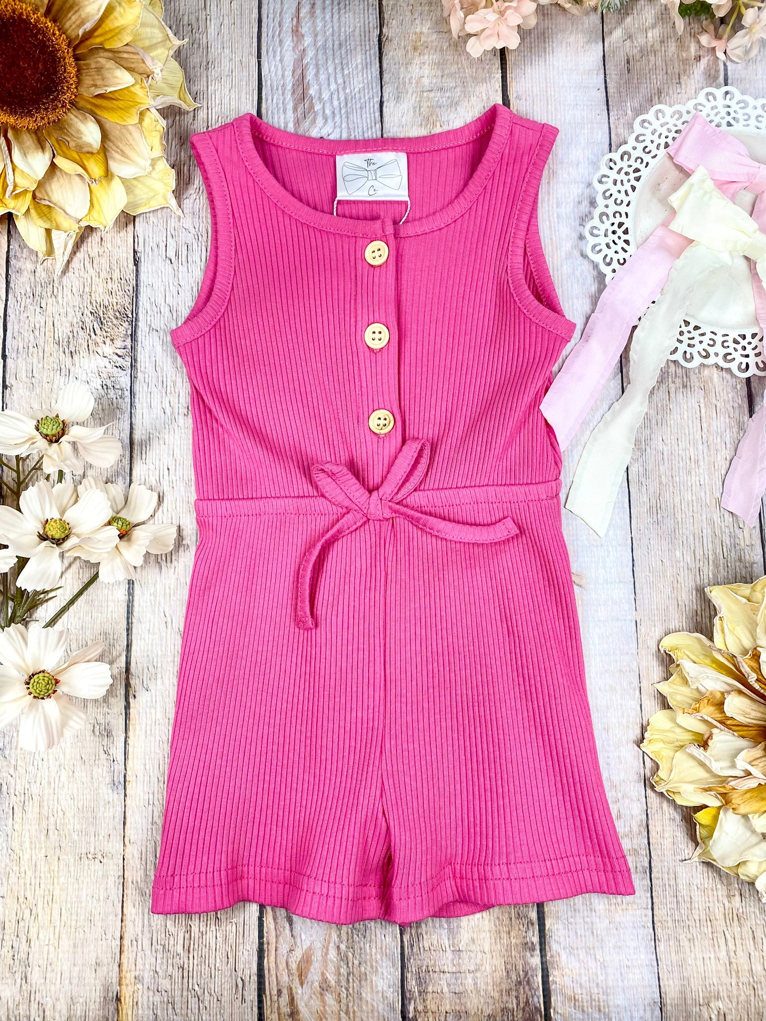 colorful romper in hot pink on a wooden background