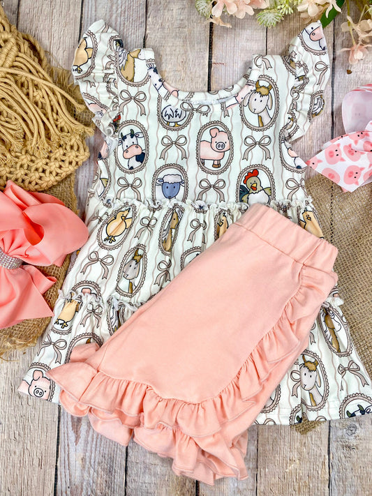 Children's outfit with patterned top and peach-colored shorts on a wooden background