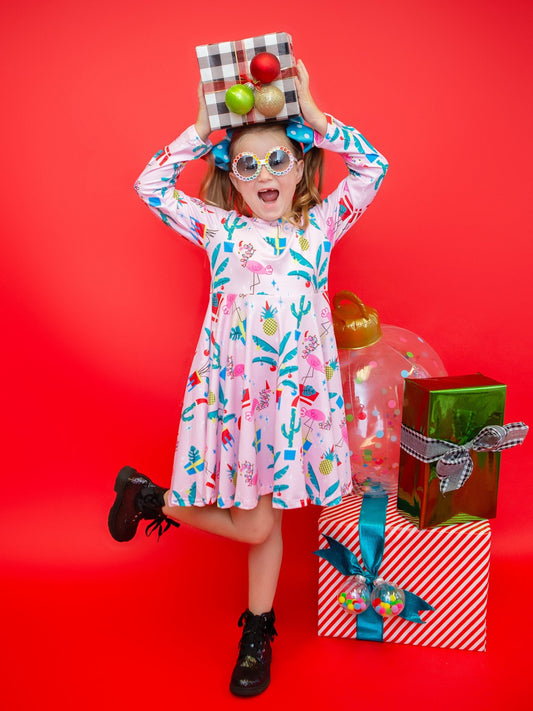 Girl wearing a flamingo Christmas twirl dress beside gift boxes