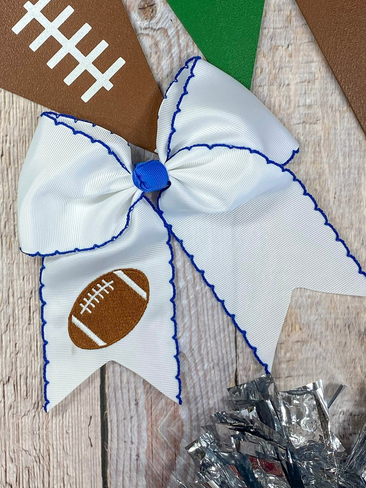 White football embroidered moonstitch cheer bow with blue stitching