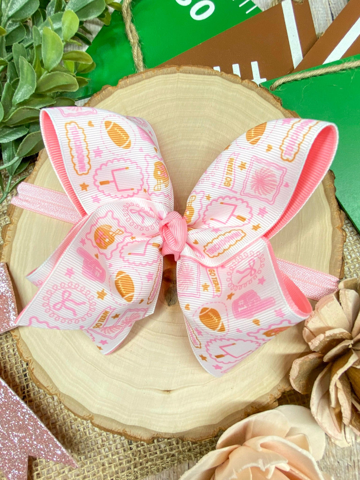 Pink football print double layer bow headband on a wooden background