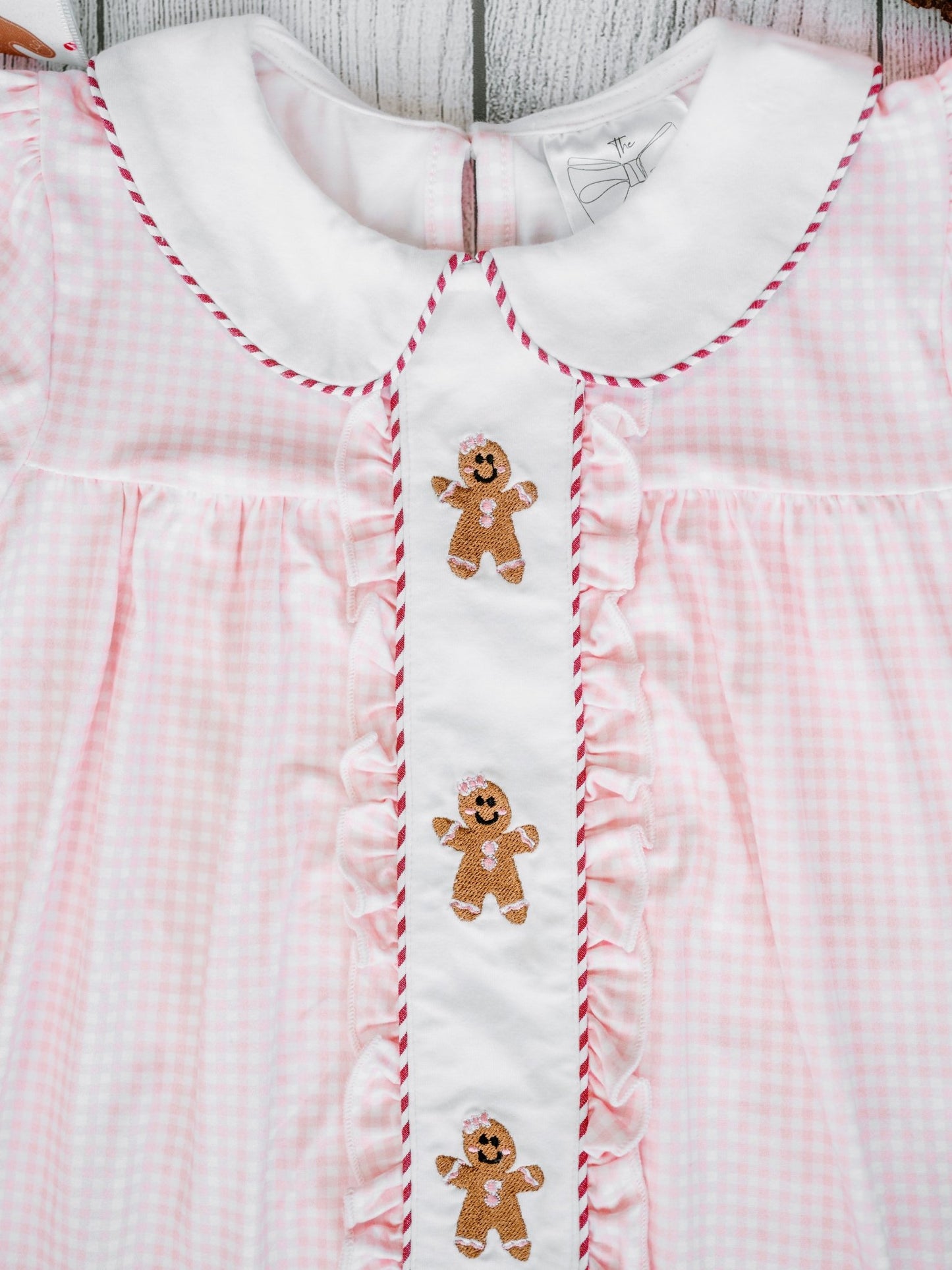 Pink checkered dress with gingerbread man designs on a wooden surface
