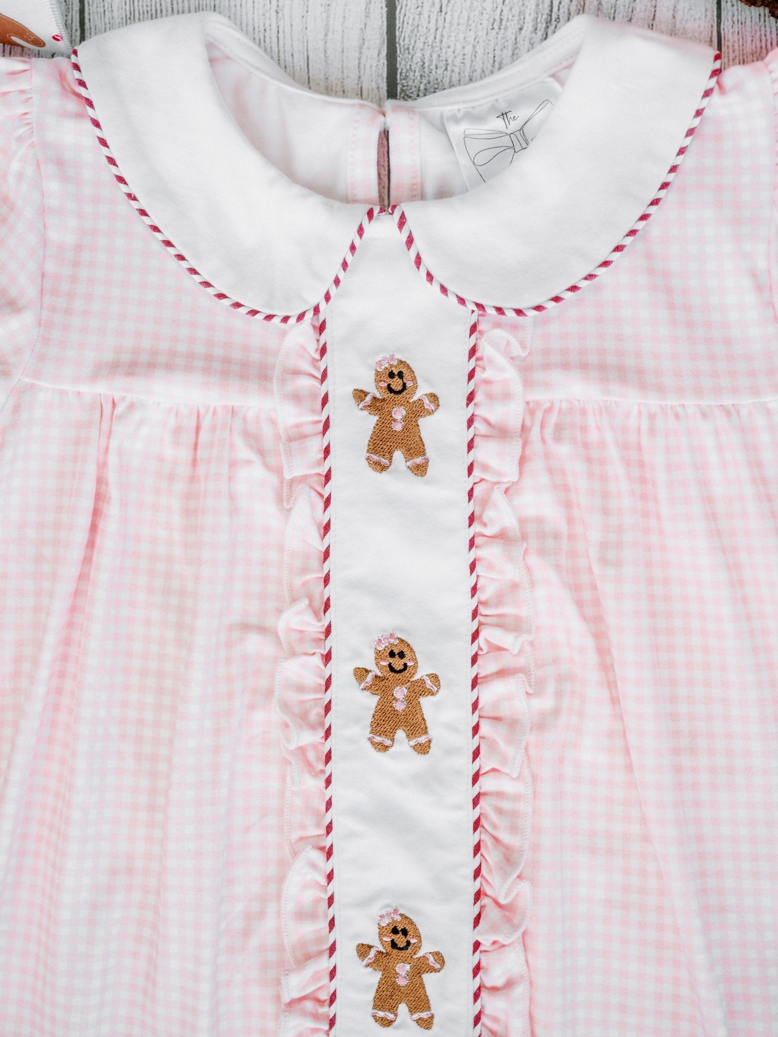 Pink checkered dress with gingerbread man designs on a wooden surface
