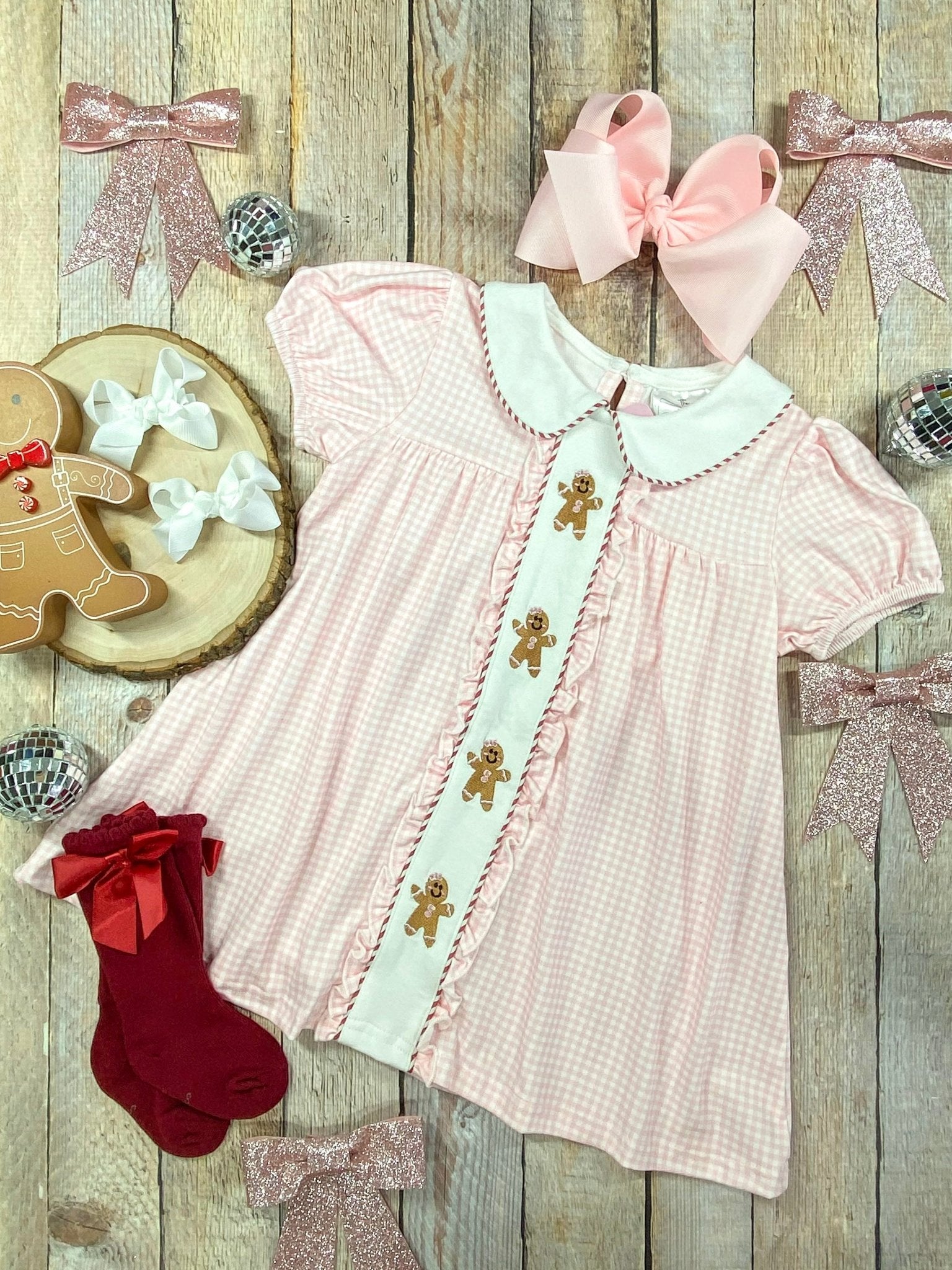 Pink gingham girls Christmas dress with embroidered gingerbread men, Peter Pan collar, and ruffle trim – perfect holiday outfit.