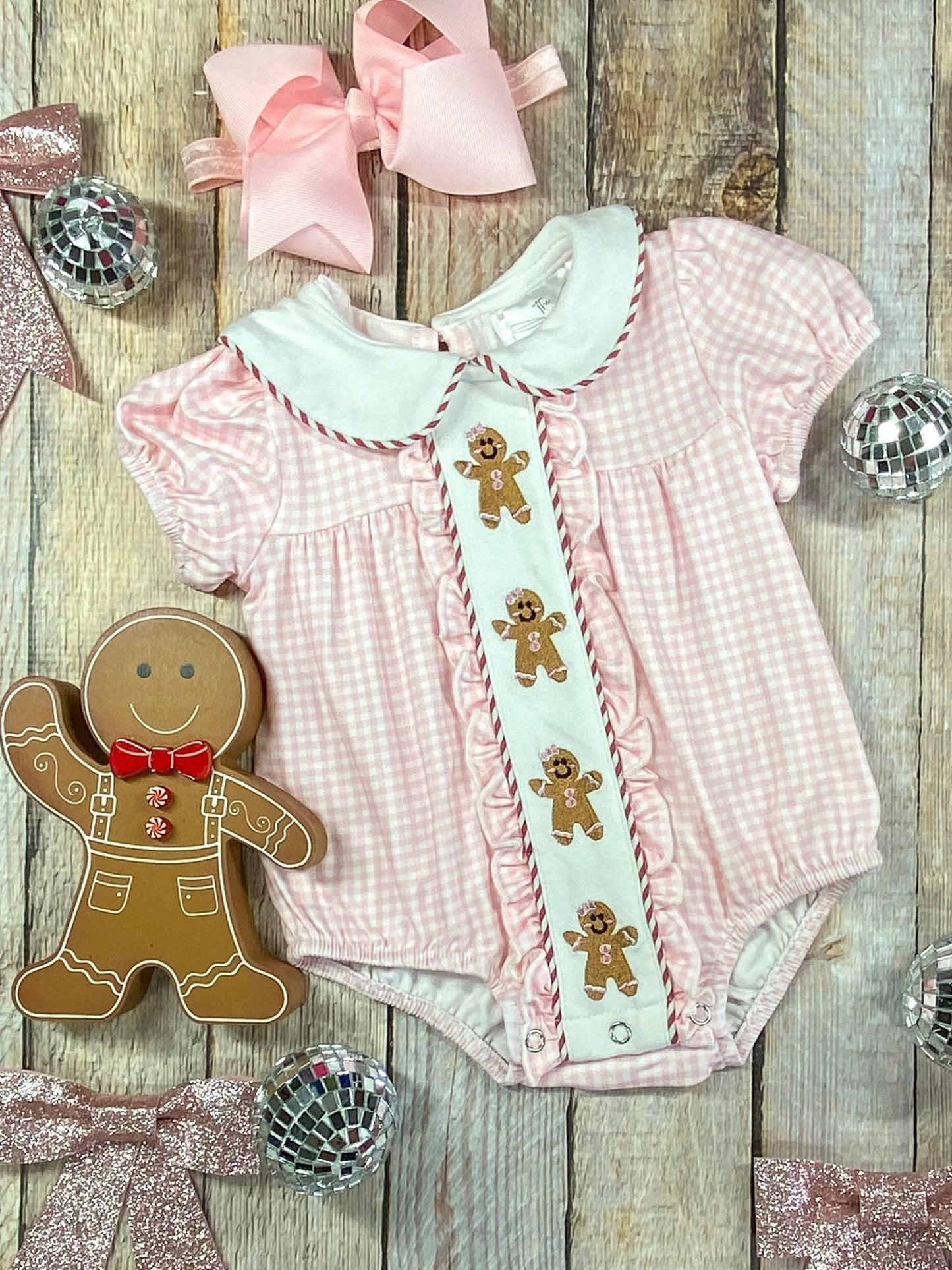 Pink gingham infant romper with embroidered gingerbread men, Peter Pan collar, and ruffle trim – perfect holiday outfit.