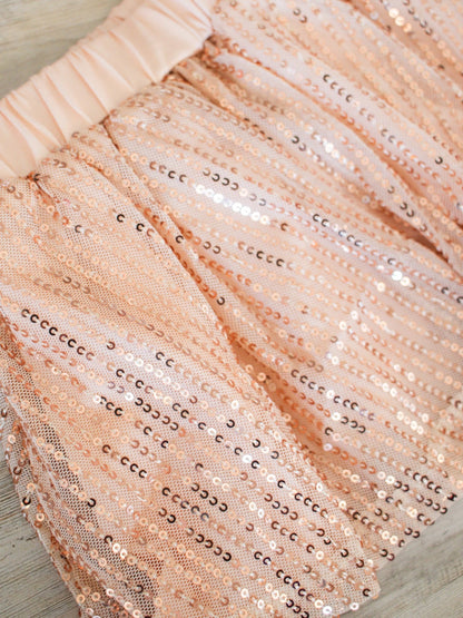 close up of the skirt- featuring a champagne or rose gold colored sequins lined on a soft tulle layered over the champagne/rose gold colored fabric
