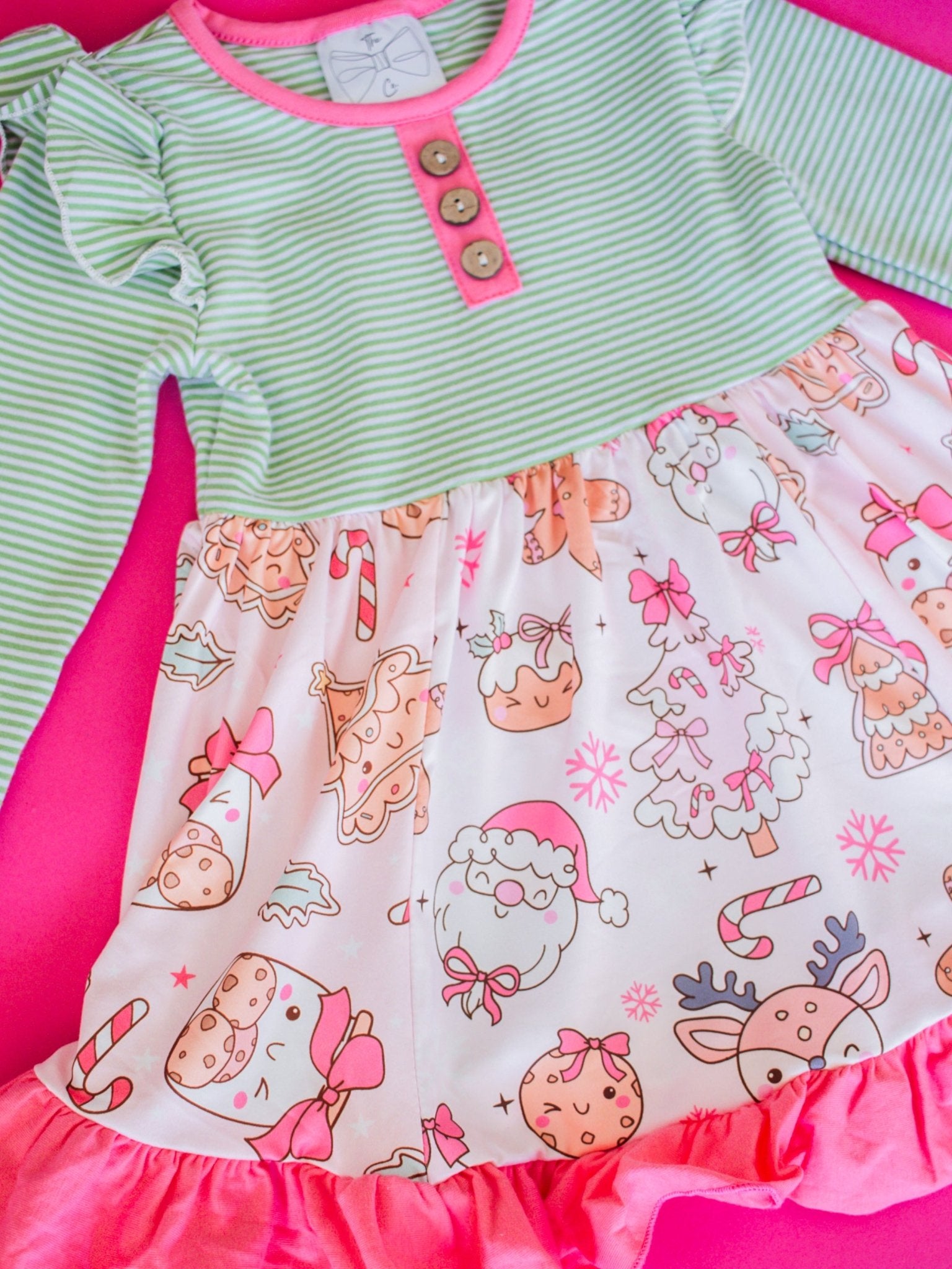 Children's dress with green top and pink skirt featuring cartoon patterns on a pink background