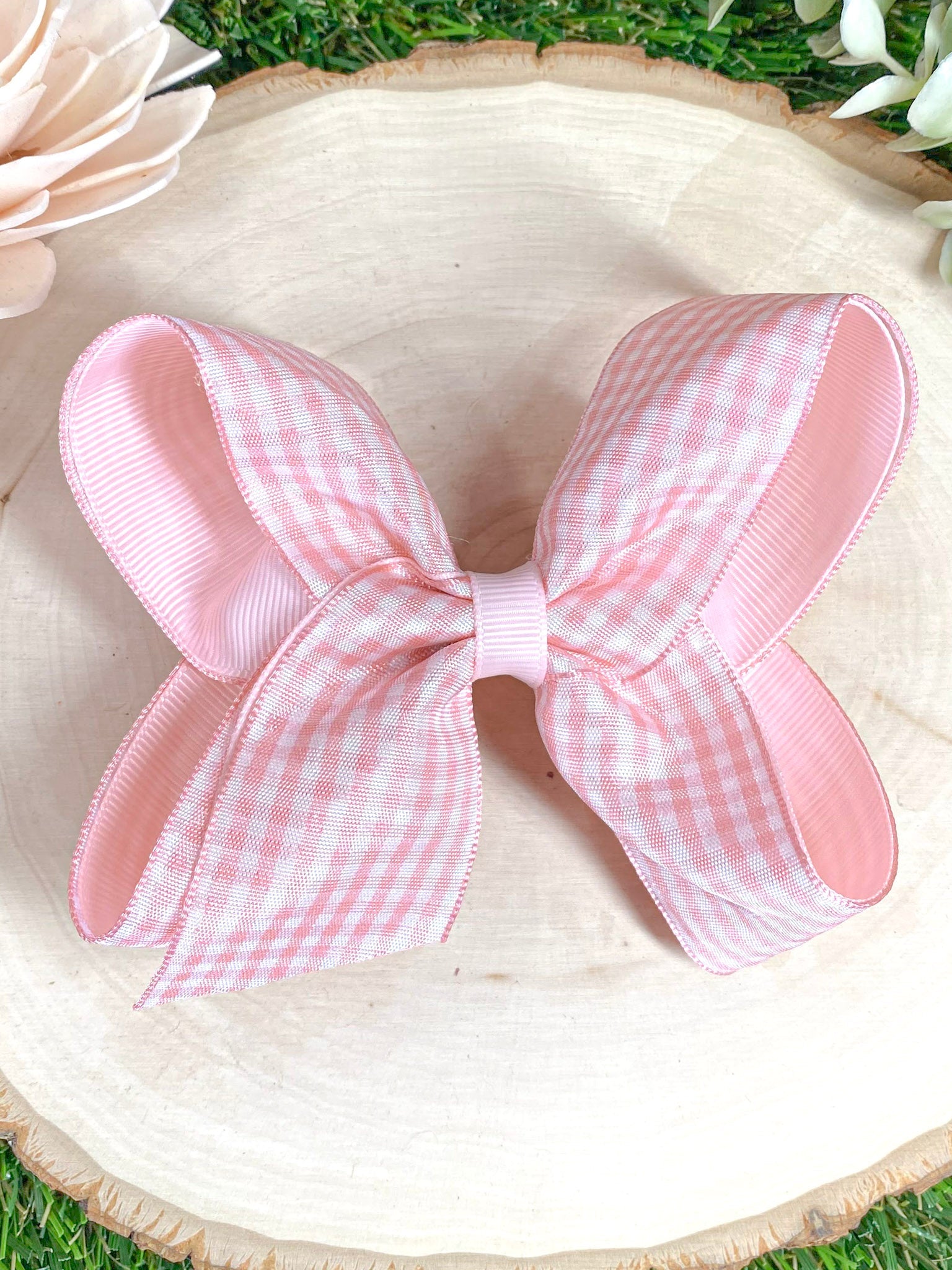 Pink gingham bow on a wooden surface 