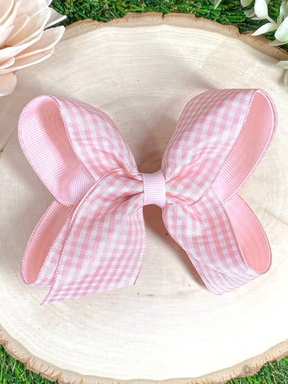 Pink gingham bow on a wooden surface 