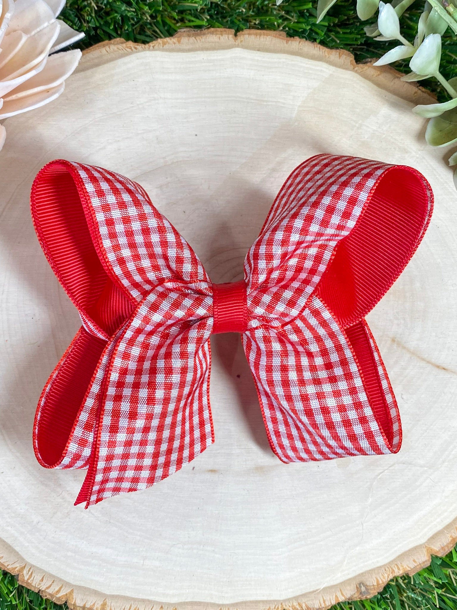 Red and white gingham bow on a wooden surface