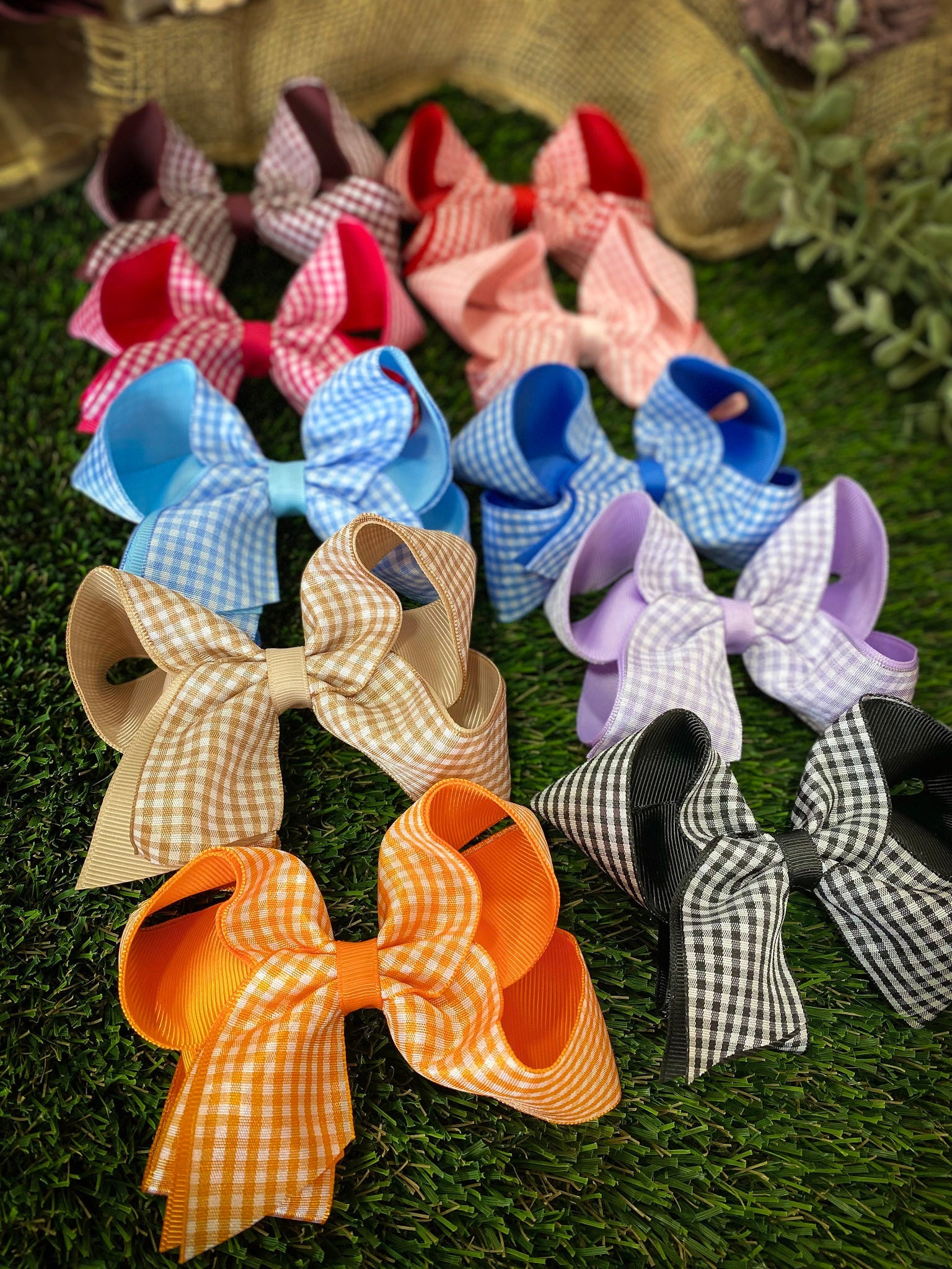 Assorted colorful gingham hair bows on a grassy background