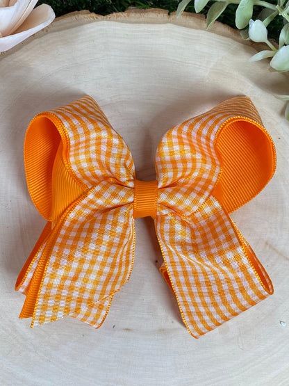 Orange and white gingham bow on a light wooden surface