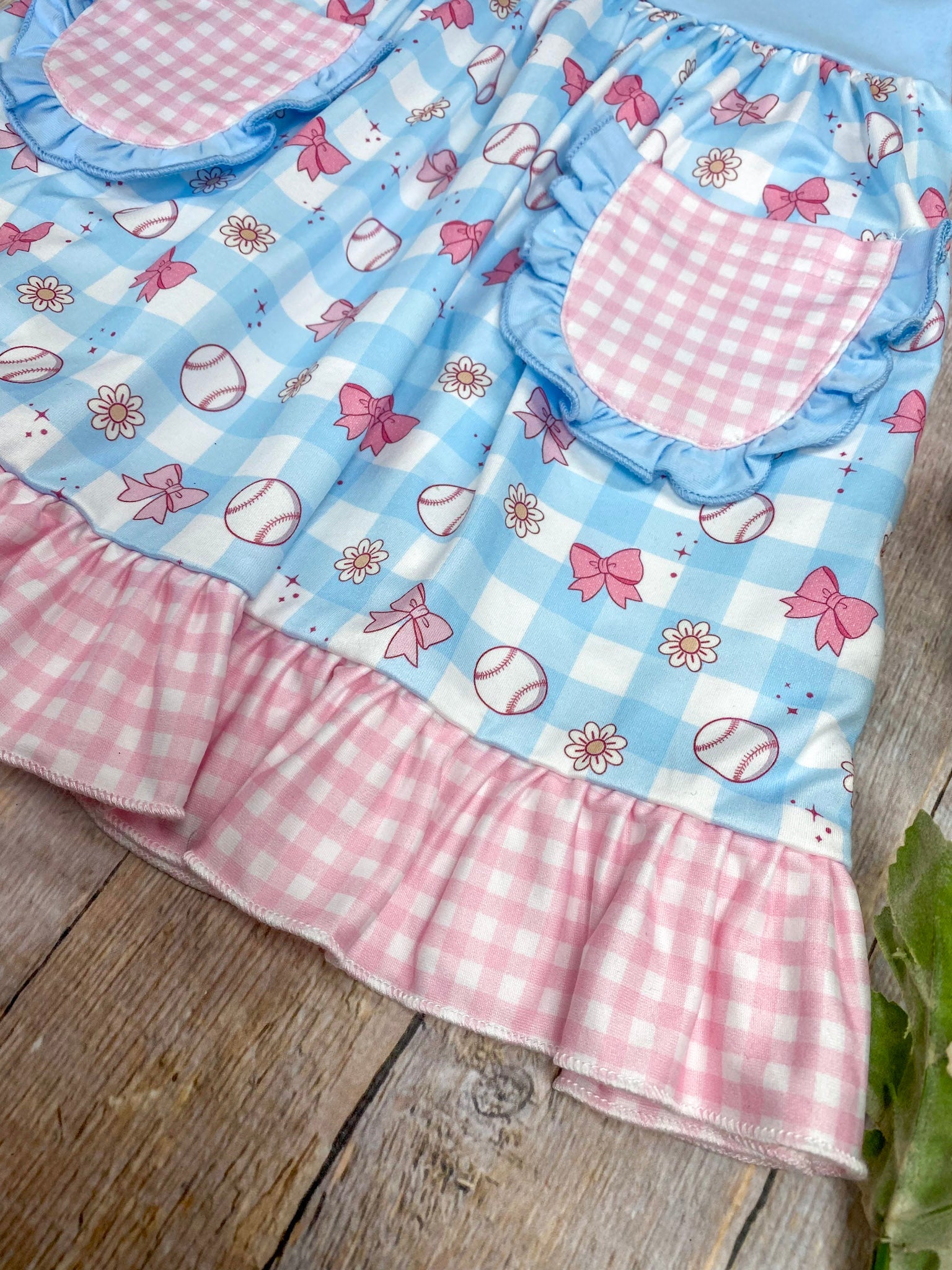 Children's apron with pink and blue checkered pattern on a wooden surface