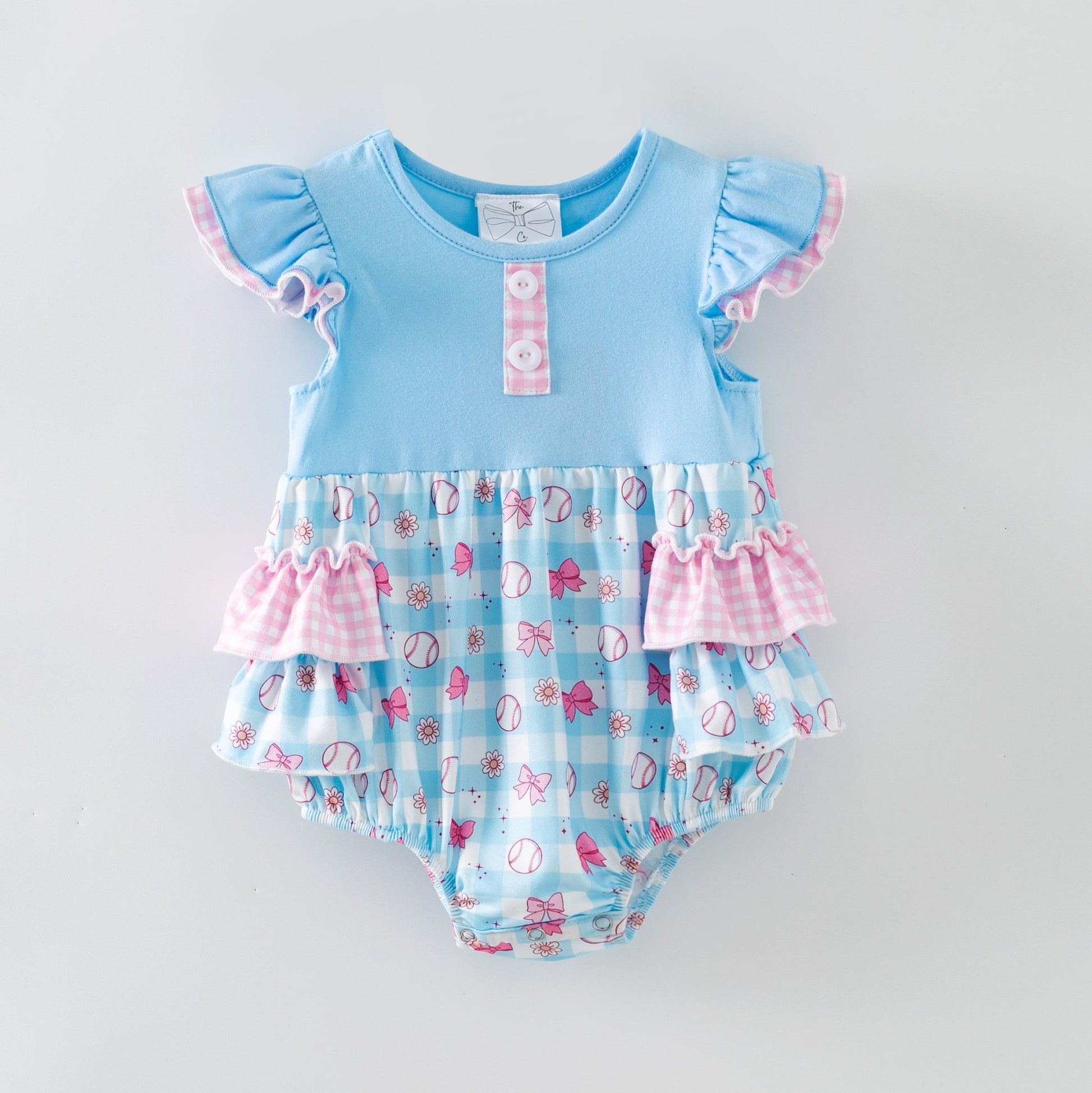 Baby romper with blue top and pink ruffles on a light gray background