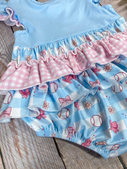 Baby romper with blue top and pink ruffles on a wooden background