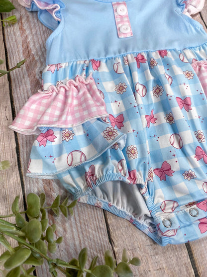 Baby romper with blue top and pink ruffles on a wooden background