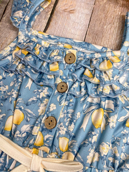 Close-up of a blue lemon romper with lemon pattern on a wooden surface