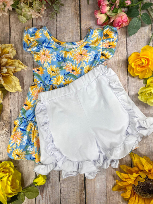 Floral top and white bloomers on a wooden surface with flowers around - Alternative view