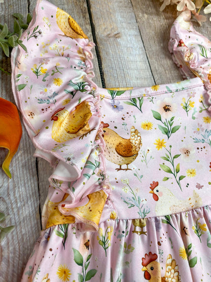 Children's dress with chicken and floral pattern on a wooden surface
