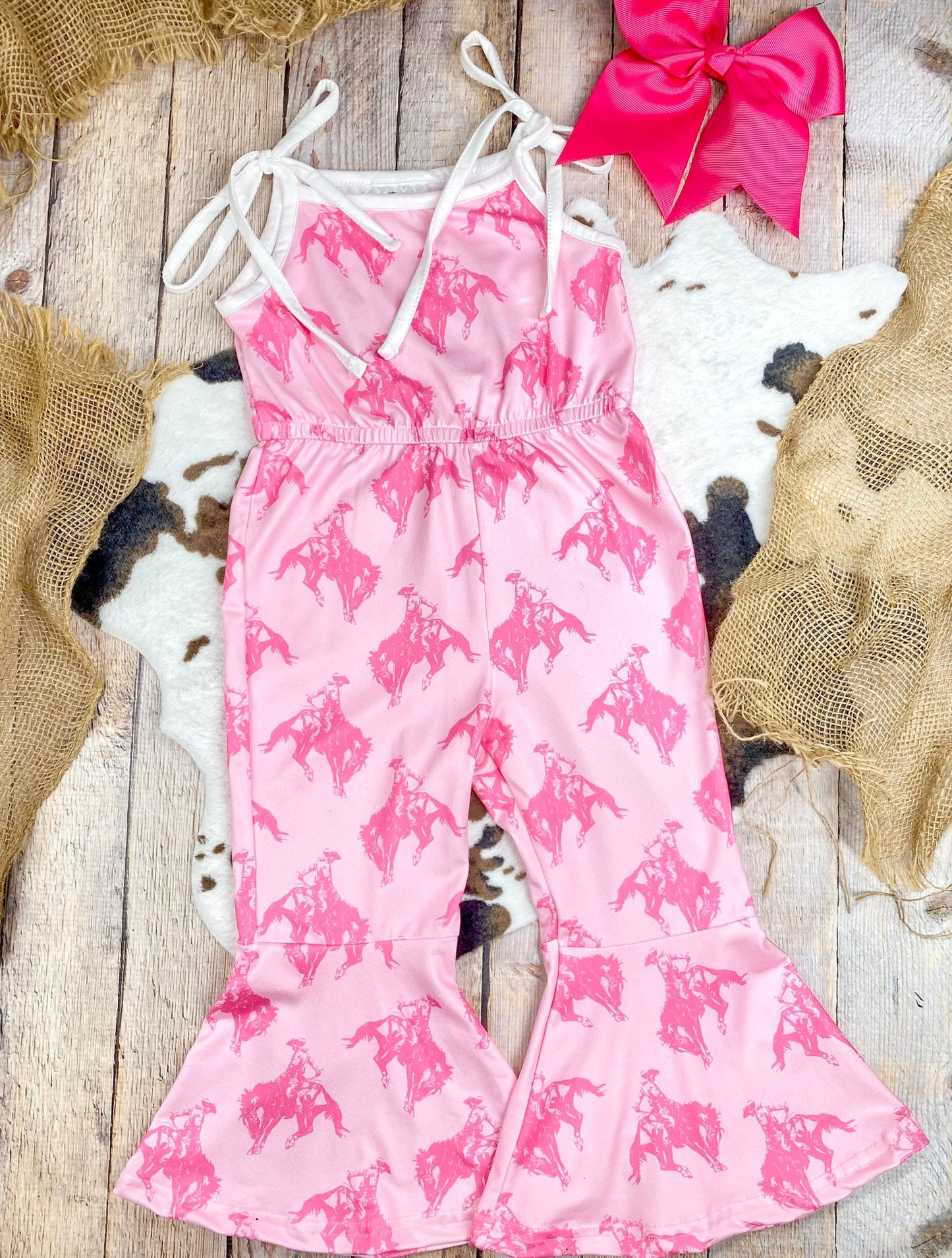 Girls Pink Rodeo Print Bell Bottom Romper on rug and wood