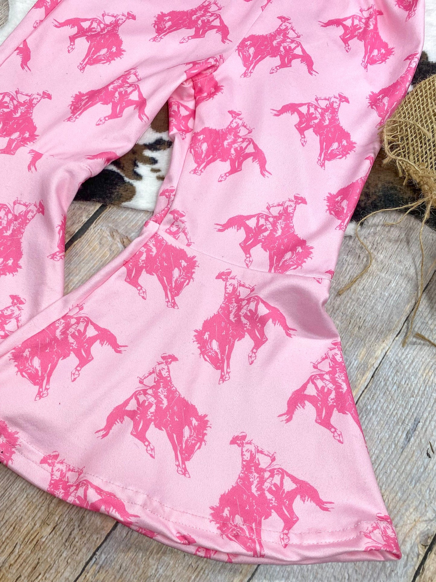 Pink fabric with horse pattern on a wooden surface