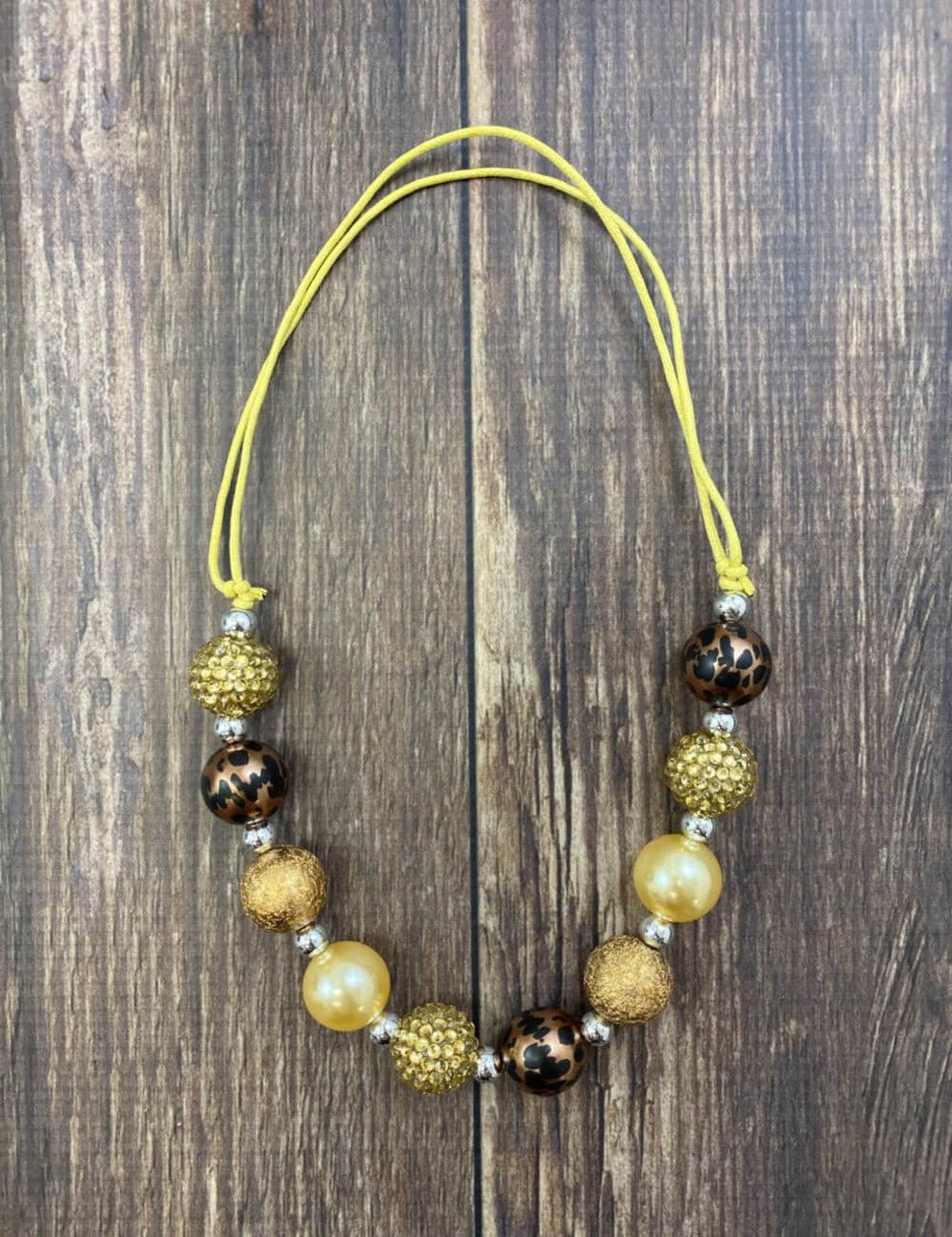 Brown, gold and animal print bead necklace on a wood table
